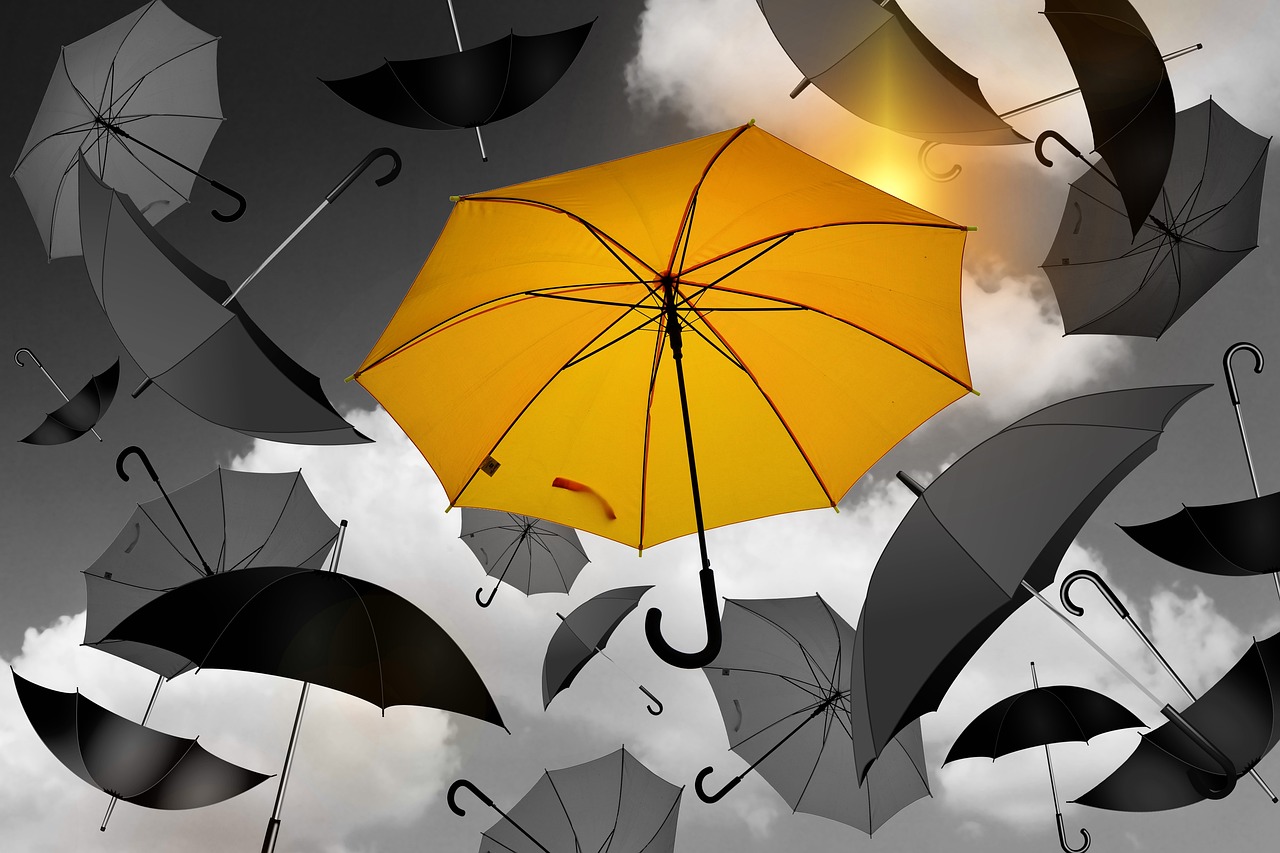 Yellow umbrella in the sky with gray and black umbrellas.
