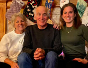 Louis Sachar with his wife, Carla Askew, and their daughter, Sherre. They are sitting in front of a fireplace hung with Christmas stockings.