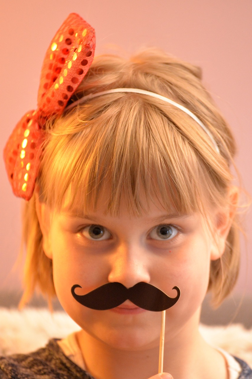 Gils with a sequined bow holding up a mustache disguise.