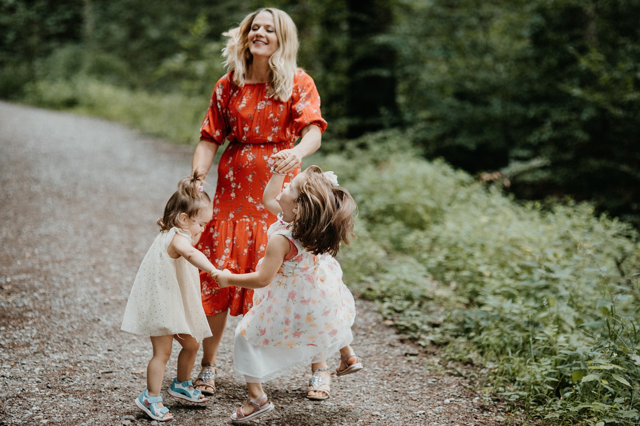 Two girls dancing with their mom outside.
