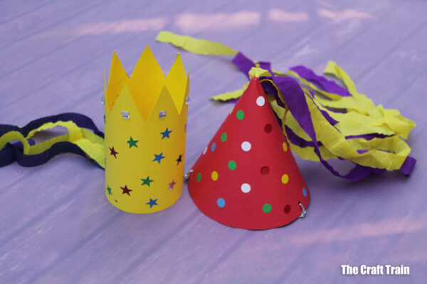 Homemade party hats, all decorated, sitting on a table.