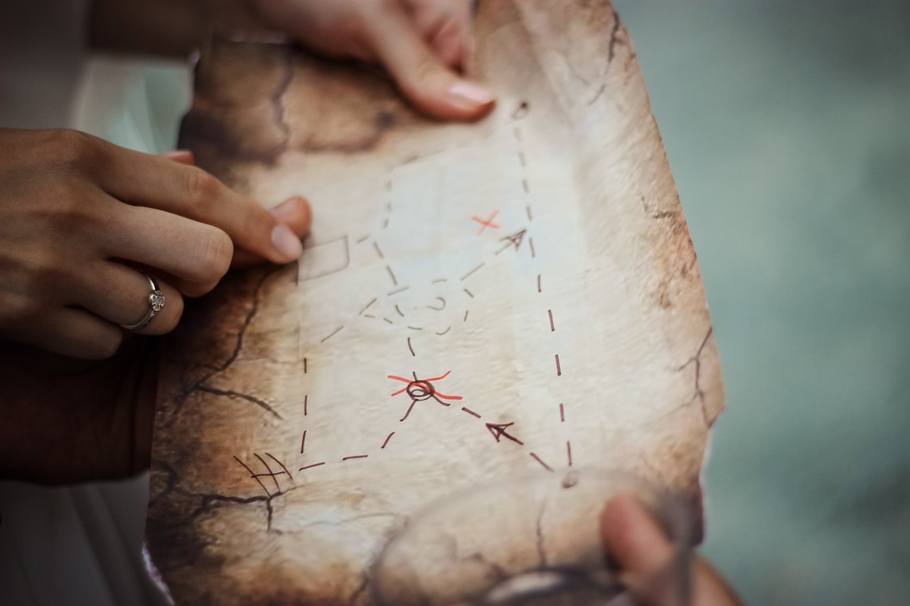 Hands holding a treasure map and tracing the route.