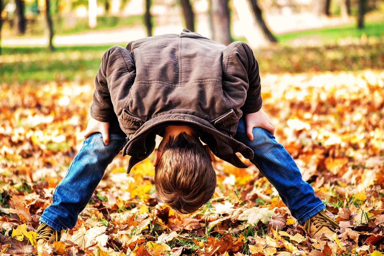 A young boy playing in the fall leaves.