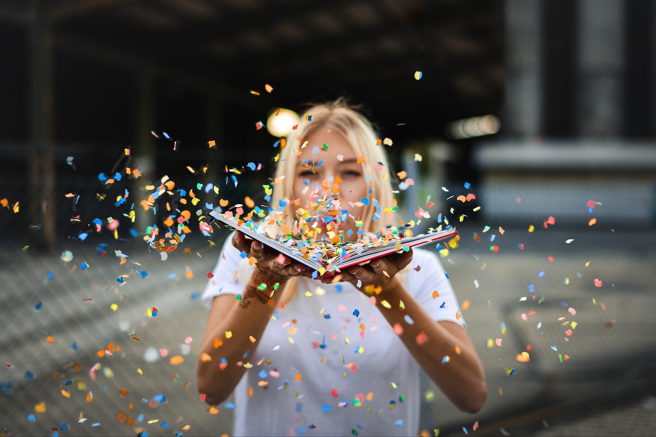 A woman blowing confetti out of a book.