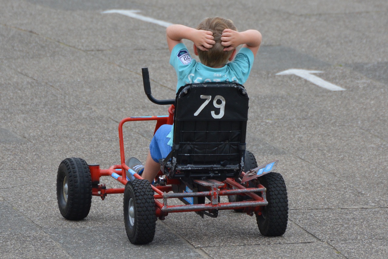 Small child sitting on a go cart, number 79.