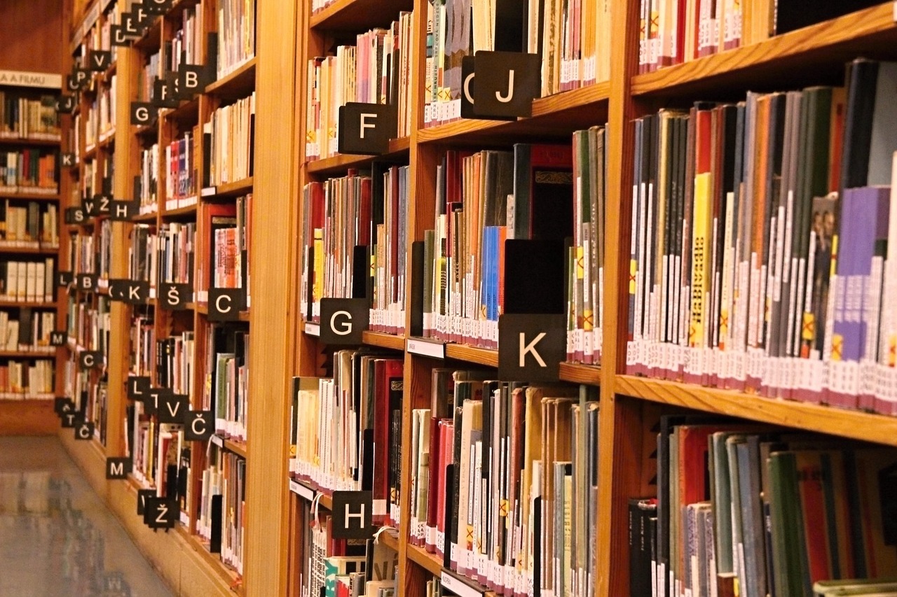 Books on shelves with letters showing their organization.