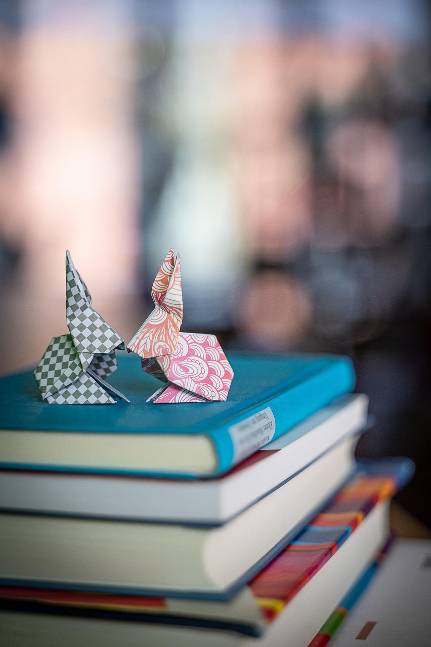 A stack of colorful books with origami rabbits sitting on top.