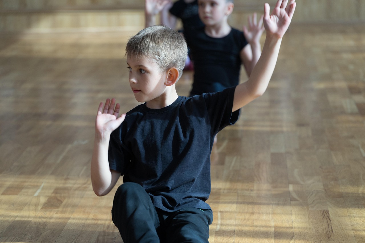 A boy, dressed in black, concentrating during dance class.