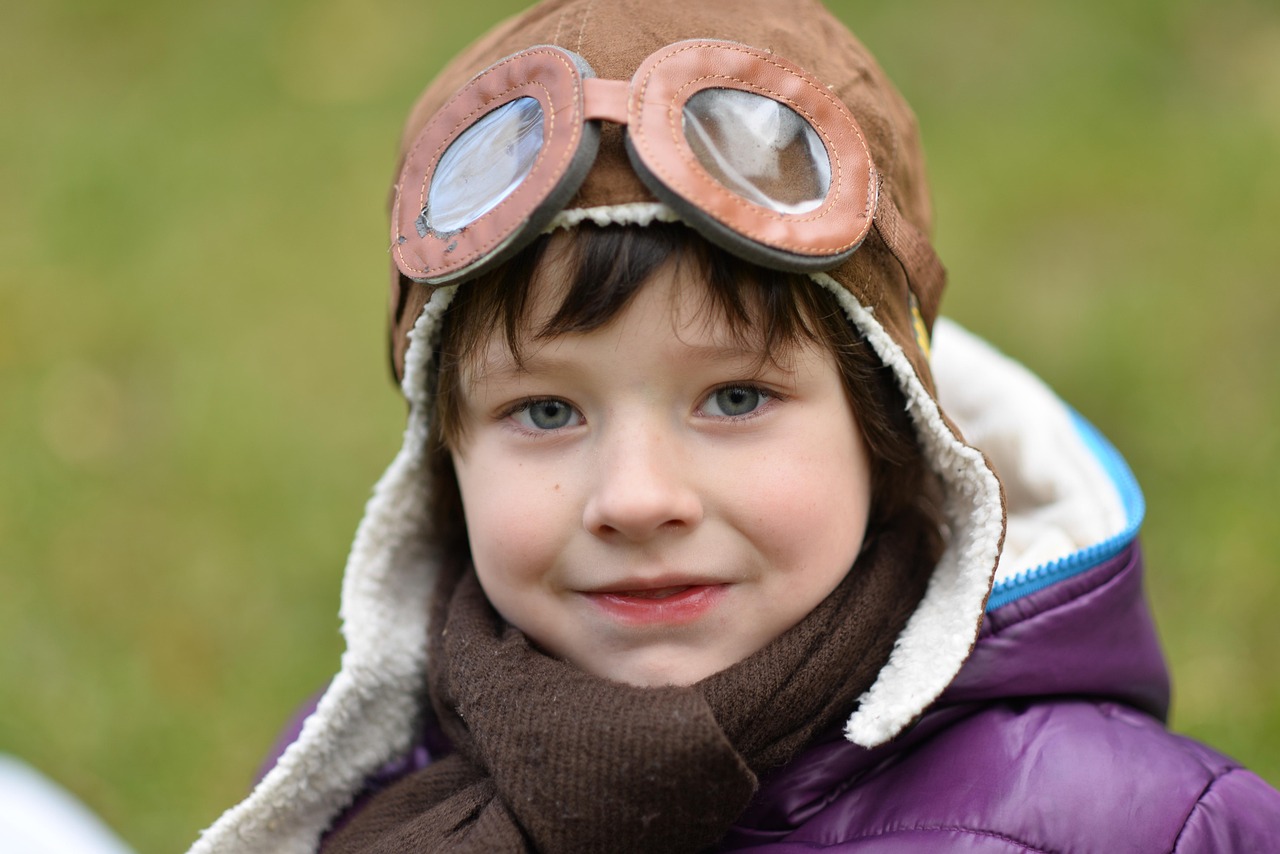Child dressed as an old-time pilot with aviator goggles and hat.