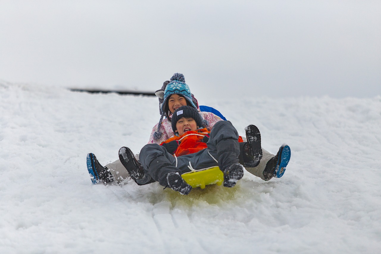 Children sledding down a snowy hill, all crowded into a toboggan.