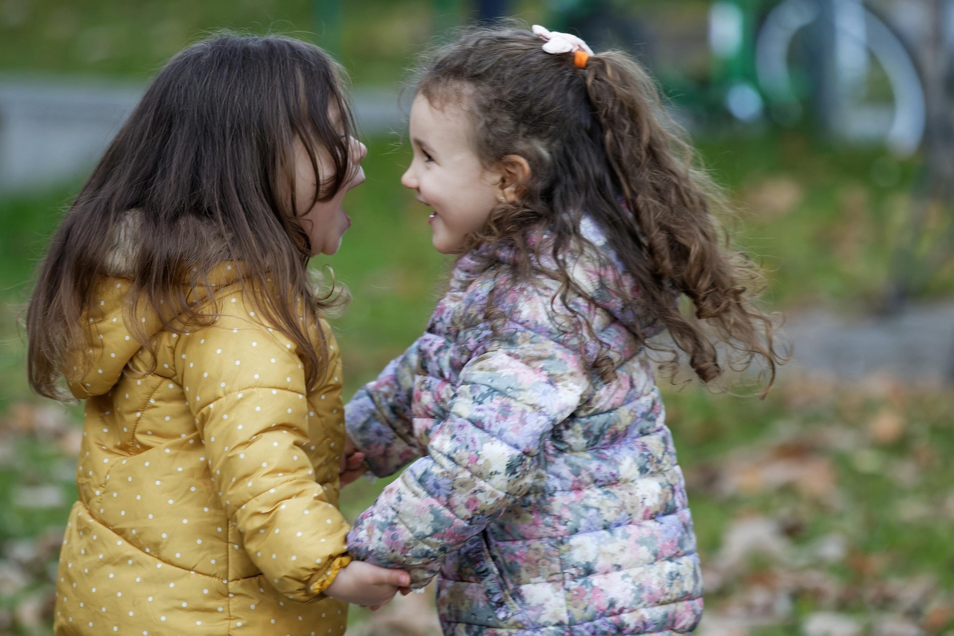 Two girls, holding hands, and playing in the spring time.